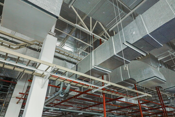 Air conditioning and ventilation system work, duct pipes covered with moisture-proof insulation on the factory ceiling