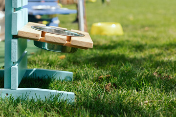 Close-up of an empty iron dog bowl with a drinking water on the grass, front view. Dog Show....