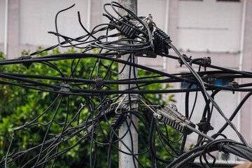 Close-up of tangled electrical wires on a city pole, showcasing the complex urban infrastructure. A Close-Up View of Urban Electrical Infrastructure background.