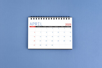 April 2025 Monthly desk calendar for 2025 year on blue background. Flat lay.