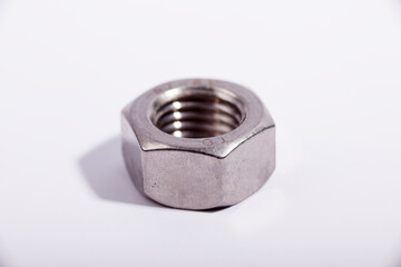 Close-up view of a stainless steel nut showcasing its intricate threading and hexagonal shape,...