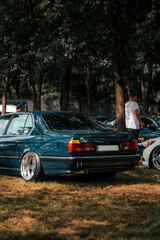 A classic showcar with a lowered stance, polished rims, and sleek design, displayed on gravel at an...