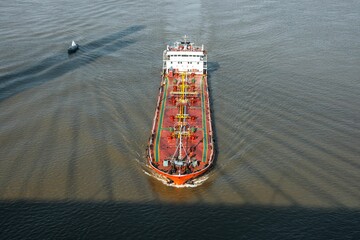 Aerial view of a red cargo ship on calm waters.