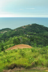 A breathtaking vista of lush green hills leading down to a tranquil ocean.