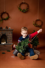 Cute handsome boy 3 years old sitting near Christmas tree eating candy