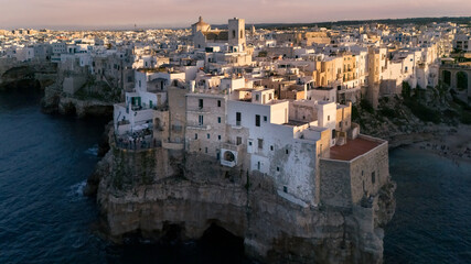 Obraz premium Aerial view of white ancient mediterranean town on rocky seaside at sunset, Polignano a Mare, Italy
