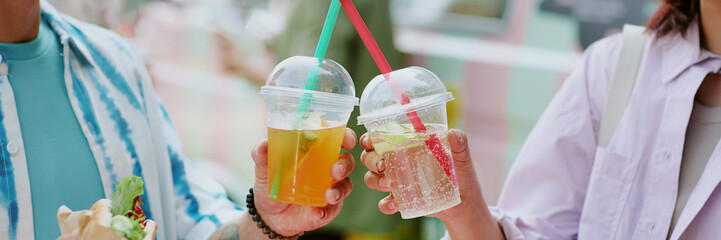 Website banner with unrecognizable couple clinking plastic cups with craft lemonade and enjoying meal