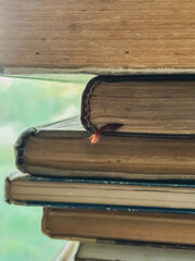 A stack of old books. Next to the window is a stack of books with a bookmark. bookmark in the book.