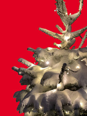 Fototapeta premium Christmas pine tree in snow with lights on red background, copy space, vertical shot