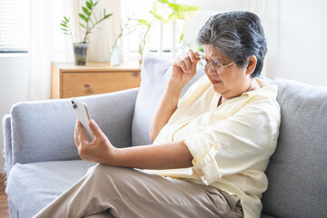 Presbyopia, Hyperopia mature, aged asian woman wearing glasses having vision problem trying to...