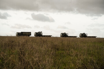Fototapeta premium a convoy of British army MAN HX utility vehicles on a dirt road