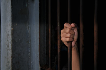 prisoner's hands behind bars