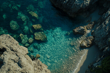 Fototapeta premium Aerial view of the beach and sea, clear water and rocks on both sides, top-down perspective, high resolution, high quality