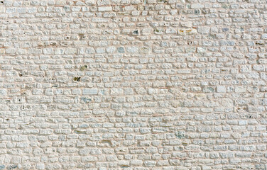 Close-up view of an old white stone wall creating a rustic and textured background, ideal for design projects