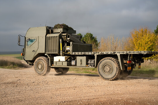 British army MAN SV HX 4x4 logistics flat-bed lorry truck with protected cab on a dirt track on a military exercise, Wilts UK