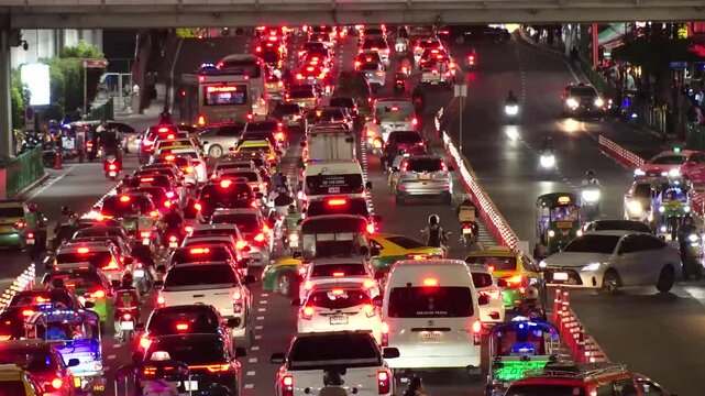 BANGKOK, THAILAND - AUGUST 2024 : High angle view of traffic jam at night. Busy rush hour at downtown shopping area. Transportation and street traffic concept video. 4K time lapse shot.