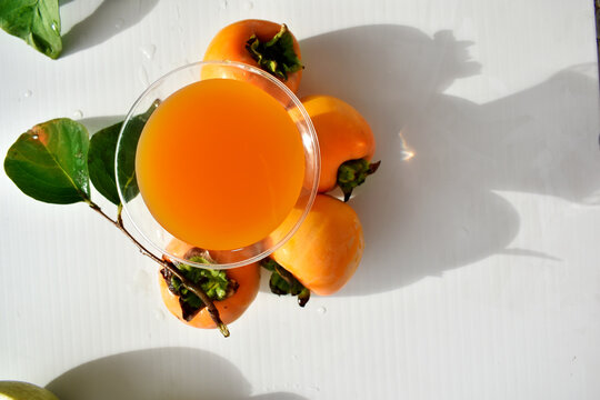 Glass of persimmon juice among persimmons