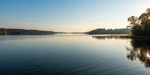 Obraz premium A serene lake on a sunny morning with gentle ripples on the water surface, serene lake, peaceful atmosphere