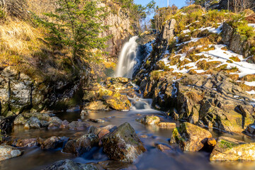 Long exposure smooth snow winter waterfall in forest Bergen Norway