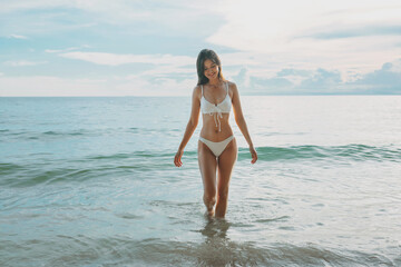 Fototapeta premium woman is walking in the ocean wearing a white bikini