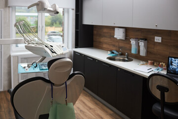 Modern dental clinic interior showing dental chair, equipment, and tools neatly organized. Room...