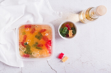Gummy bears soaked in lemonade prepared for frozen candy in container on table top view