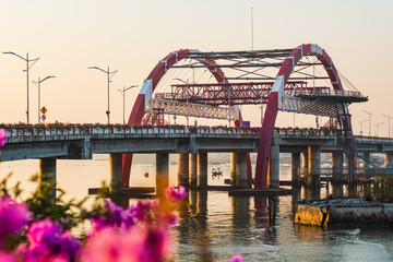 Fototapeta premium Beautiful Panoramic Golden Morning in Surabaya Bridge Kenjeran with Flower Foregrounds. 