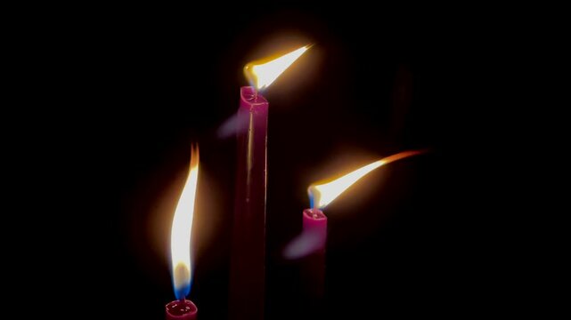 Red burning candles in the dark close up slow motion