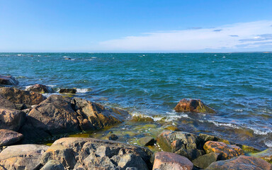 A serene and calm coastal scene featuring dramatic rocks alongside a clear blue sea