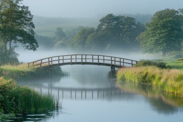 Obraz premium Wooden bridge reflecting in a misty river at sunrise in the countryside