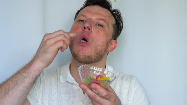 A young man eats worm jelly candies in slow motion. Sweet jelly candies in the hands of a man