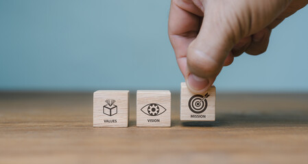 The company's mission, vision, values. purposeful business idea. A hand holds a wooden cube with symbols for purpose, vision, values. contemporary vertical layout. presentation for business. Banner
