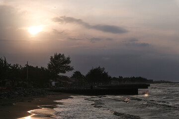  breathtaking sunset paints the sky with hues of orange and pink. The sun dips below the horizon, casting a warm glow on the beach and the ocean waves