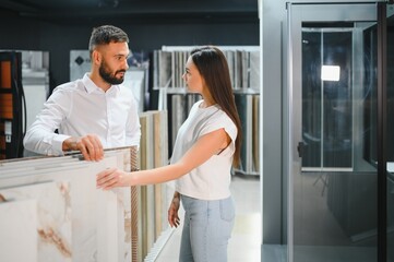 Obraz premium Salesman and a female customer choosing a right ceramic tile for her home, at the home design store