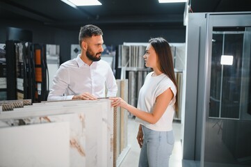 Obraz premium Young woman with sales man choosing tiles at building market