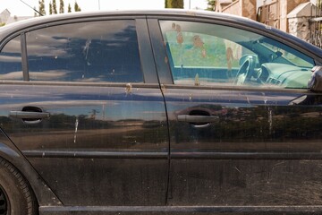 Dust-Covered Black Sedan Parked Against Urban Backdrop