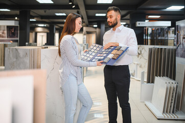 Salesman and a female customer choosing a right ceramic tile for her home, at the home design store