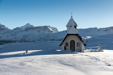 Sunny view of a little chapel near the ski piste in the Alta Badia ski area
