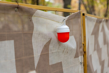 A red signal light hangs from a fence warning passersby of danger