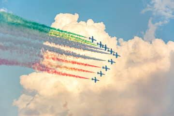 Fighter jets performing airshow with colorful exhaust streams in scenic clouds