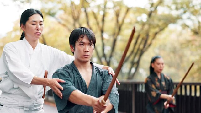 Japan, student and stick with mentor, help and exercise with fitness, outdoor or practice. People, karate or weapon in park, workout or kenjutsu with energy, learning or sensei with advice or warrior