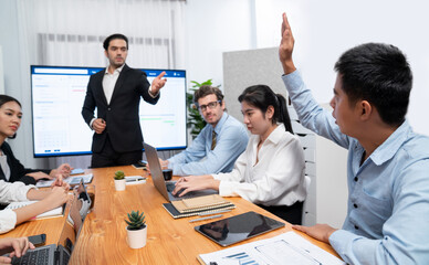 Corporate employee raise hand ask question during project meeting, businessman or manager explaining business task planning schedule with timeline software show on TV screen. Habiliment