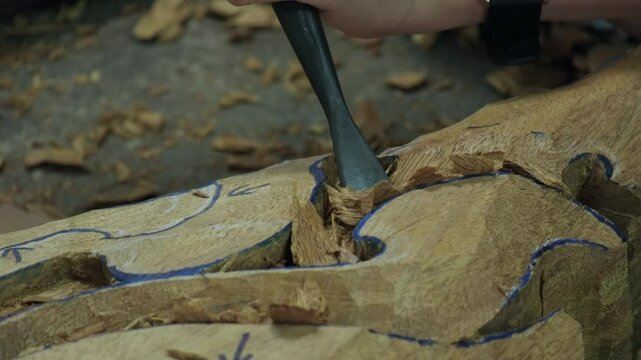 Craftsman makes wood carving with chisel close-up.