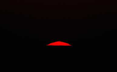 Image of a scenic long focal length spectacular sunset. Big sun over the horizon in the evening.