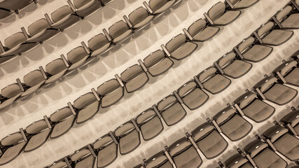 Overhead image of empty tan / gray theater, auditorium seats, chairs.	