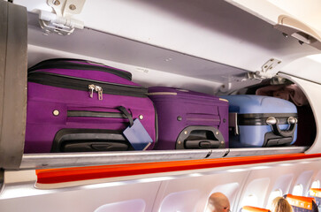 Hand luggage and suitcases inside the cabin overhead lockers of a passenger plane