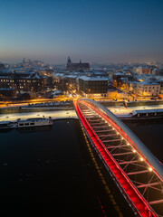 Fototapeta premium Bernatka footbridge over Vistula river in Krakow, Poland, illuminated in the winter evening