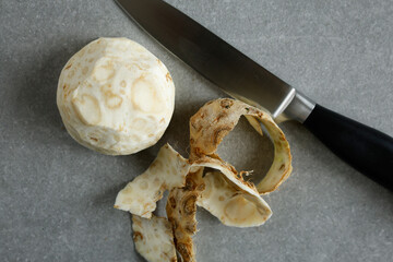 celery root with a kitchen knife on gray surface