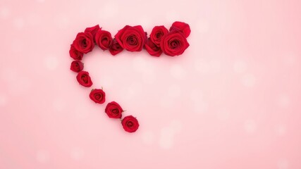 Obraz premium A heart-shaped arrangement of red roses on a soft pink background, creating a delicate and romantic backdrop.