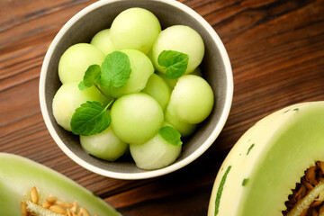 Melon balls in bowl and fresh fruit on wooden table, flat lay